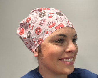 Könnte beinhalten: Eine rosa OP-Mütze mit einem Donut- und Kaffeetassenmuster. Die Mütze hat die Worte "Love You" und "XOXO" aufgedruckt.