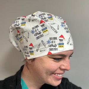 May include: A white scrub hat with a repeating pattern of a syringe, a bottle labeled "Propofol 10 mg/ml", and the text "Dreaming of a White Christmas". A red Santa hat is on top of the bottle.