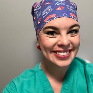 May include: A blue scrub hat with a white and red pattern. The hat has the text "I Pass Gas For A Living #Anesthesia" printed on it.