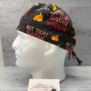 May include: Black scrub cap with a red and yellow print that says "Not Today, Satan" and "Satan Surgeon".