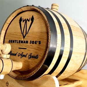 May include: A wooden barrel with black metal bands and a spigot. The barrel is labeled "Gentleman Joe's - Barrel Aged Spirits".