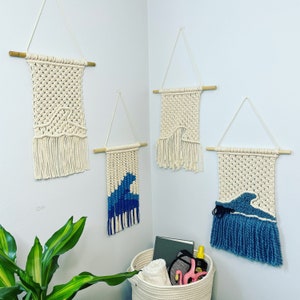 May include: Four macrame wall hangings with fringe. Three are white with a woven pattern and one has a blue wave design.