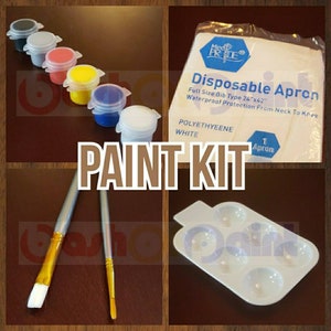 K&ouml;nnte beinhalten: Ein Malkasten mit sieben kleinen Farbt&ouml;pfen, zwei Pinseln, einer Plastik-Farbpalette und einer Einweg-Sch&uuml;rze. Die Farbt&ouml;pfe sind mit den Farben Schwarz, Grau, Rot, Gelb, Blau und Wei&szlig; beschriftet. Die Sch&uuml;rze ist wei&szlig; und hat den Text "Disposable Apron" aufgedruckt.