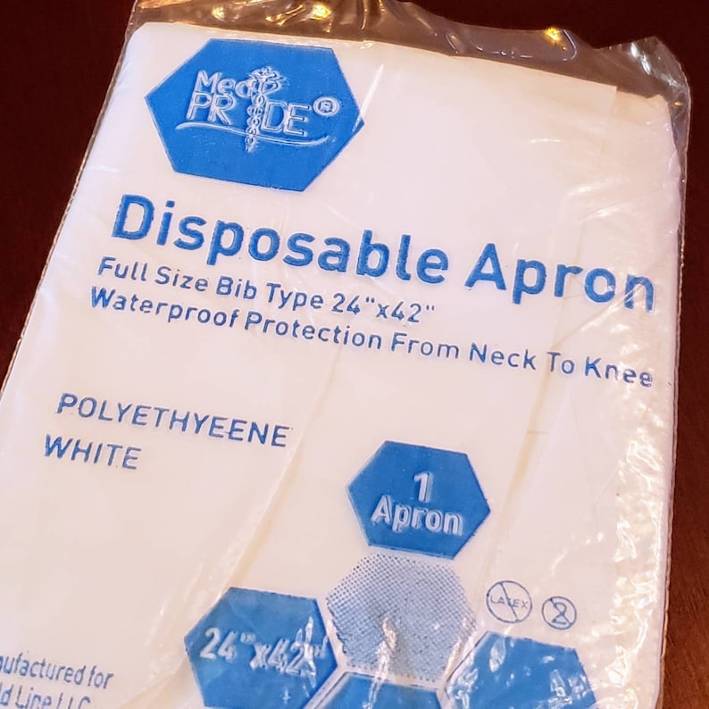 May include: A white disposable apron with blue text and a blue logo. The text reads "Disposable Apron", "Full Size Bib Type 24"x42"", "Waterproof Protection From Neck To Knee", "POLYETHYEENE", "WHITE", and "1 Apron".
