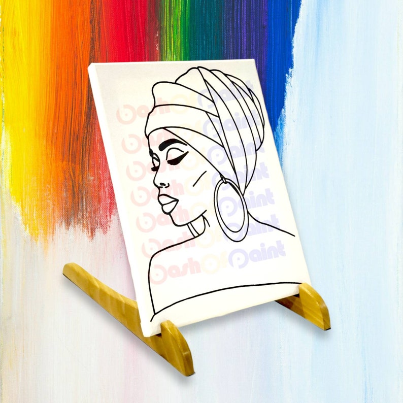 May include: A black and white line drawing of a woman wearing a headscarf and large hoop earrings. The drawing is on a white canvas with a wooden easel.
