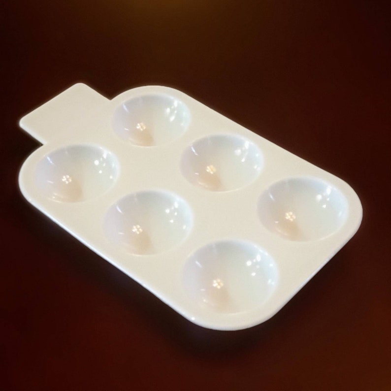 May include: White plastic paint palette with six round wells.