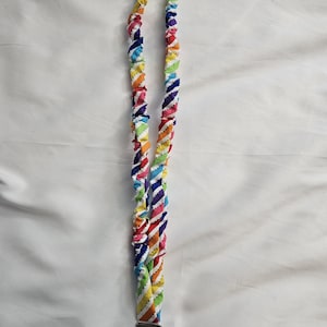May include: A colorful lanyard with a rainbow striped pattern. The lanyard is made of fabric and has a silver-colored metal clasp and key ring at the bottom. The fabric is twisted, creating a rope-like appearance.