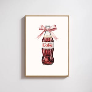 Puede incluir: Pintura a la acuarela de una botella de Coca-Cola Light con un lazo rosa. La botella es roja con una etiqueta blanca que dice "Diet Coke". El lazo está atado alrededor del cuello de la botella. La obra de arte está enmarcada en un marco marrón claro.