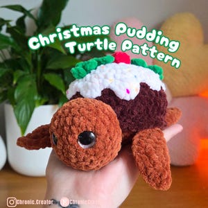 May include: A crocheted turtle shaped like a Christmas pudding. The turtle is brown with a white and brown pudding top, decorated with green leaves and a red cherry. The text "Christmas Pudding Turtle Pattern" is displayed.