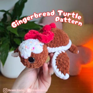 May include: A handmade brown crochet turtle with a white and sprinkle-covered head, a red bow, and white trim. The text "Gingerbread Turtle Pattern" is displayed in a red bubble font. The turtle is held in a hand.