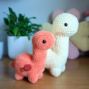 Pu&ograve; includere: Due giocattoli di dinosauro all'uncinetto, uno &egrave; di colore arancio chiaro e l'altro &egrave; di colore crema. Entrambi i dinosauri hanno gli occhi neri.