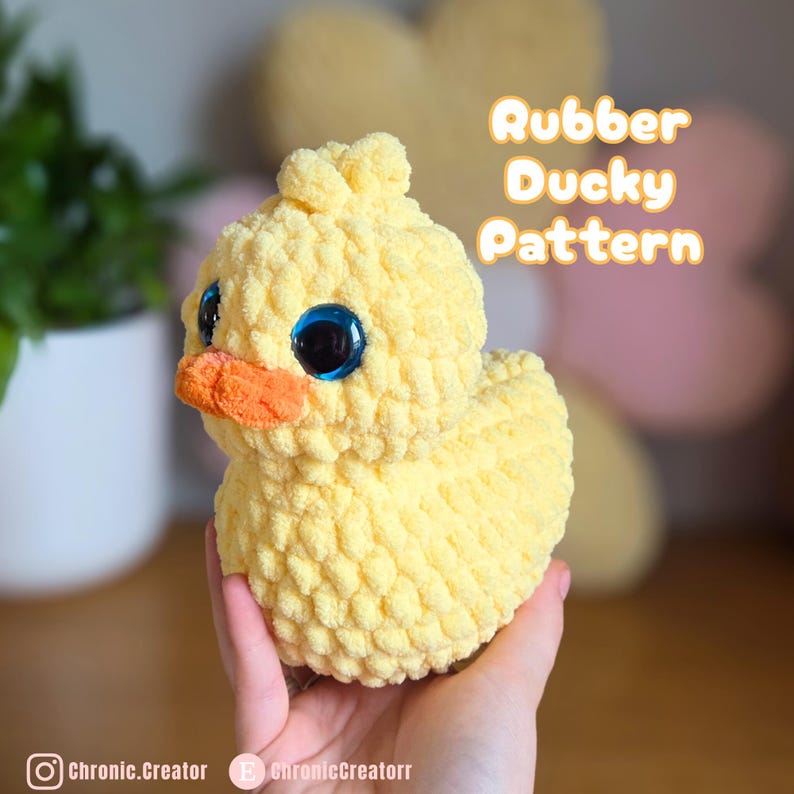 May include: A handmade yellow crochet duck with large blue eyes and an orange beak. The text "Rubber Ducky Pattern" is displayed in an orange font. The duck is a soft, plush toy.