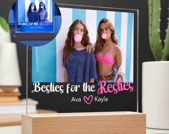 Op de afbeelding: Een verlicht fotolijstje met een foto van twee meisjes die kauwgom blazen. Het lijstje heeft een houten voet en de tekst "Besties for the Resties Ava Kayla" is op het lijstje gedrukt.