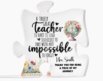 May include: A clear acrylic puzzle piece with a floral design and a globe. The text reads "A truly great teacher is hard to find, difficult to part with and impossible to forget."  The text also includes "Mrs. Smith, Thank you for being a piece of my journey."