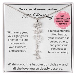 May include: A silver necklace with a pendant featuring the name "Elizabeth" in cursive script, accented by a flower design. The necklace is presented on a white card with birthday wishes and the text "With Personalized Name & Birth Flower."