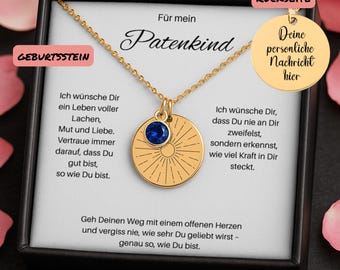 May include: Gold-colored pendant necklace with a round charm featuring a blue gemstone and engraved sunburst design. The necklace is presented in a black box with German text, including "Für mein Patenkind" and "Deine persönliche Nachricht hier."