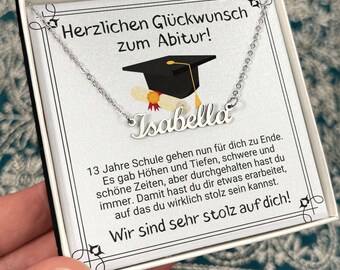 May include: A silver necklace with a graduation cap charm and the name "Isabella" on it. The necklace is in a white gift box with a message that says "Herzlichen Glückwunsch zum Abitur!" which translates to "Congratulations on your graduation!" in English. 13 Jahre Schule gehen nun für dich zu Ende. Es gab Höhen und Tiefen, schwere und schöne Zeiten, aber durchgehalten hast du immer. Damit hast du dir etwas erarbeitet, auf das du wirklich stolz sein kannst. Wir sind sehr stolz auf dich! which translates to "13 years of school are now over for you. There were highs and lows, difficult and beautiful times, but you always persevered. You have earned something to be truly proud of. We are very proud of you!" in English.