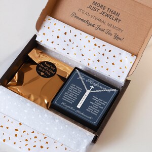 a gift box with a gold-colored bag inside, and a necklace with a pendant inside the box. The box is open, and the contents appear to be a personalized gift.