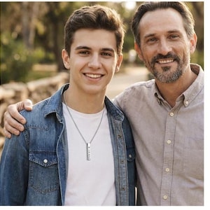 A young man and an older man stand together, smiling and embracing each other.