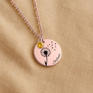 A necklace with a pendant featuring a dandelion design and a yellow gemstone.