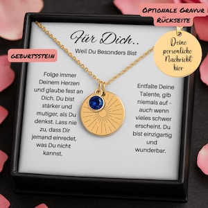 Op de afbeelding: Een goudkleurige ketting met een ronde hanger met een zonnestraalontwerp en een blauwe edelsteen. De ketting wordt gepresenteerd in een zwarte doos met Duitse tekst. De hanger is bevestigd aan een fijne ketting.