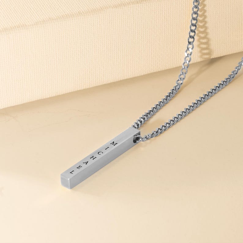 A silver necklace with a rectangular pendant that has the word "MATH" engraved on it.