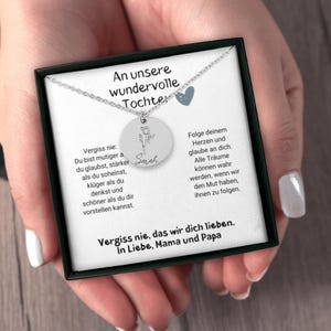 a woman's hands holding a necklace in a box