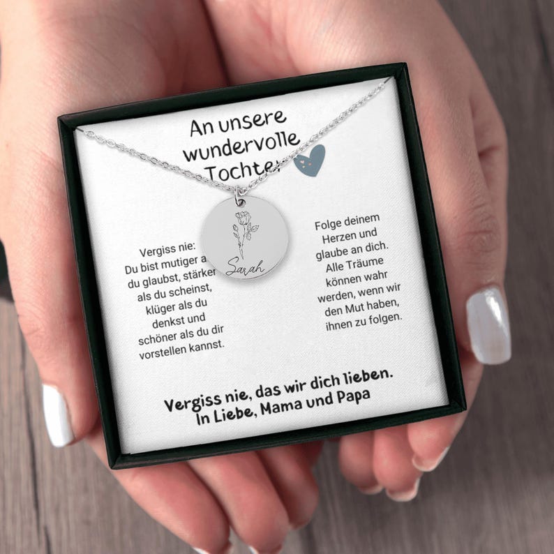 a woman's hands holding a necklace in a box