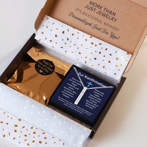 a gift box with a gold-colored package inside, and a necklace with a pendant visible. The box has a label that reads "More than just jewelry, it's an eternal memory personalized just for you!"