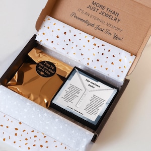 an open box containing a necklace and a card
