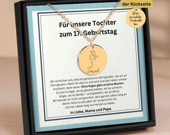 May include: A gold necklace with a round pendant featuring a delicate flower design and the name "Sarah" engraved on it. The necklace is displayed in a black box with a message for a daughter on her 17th birthday. The message reads "For our daughter on her 17th birthday".