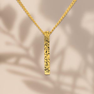 A gold necklace with a pendant featuring a geometric design.