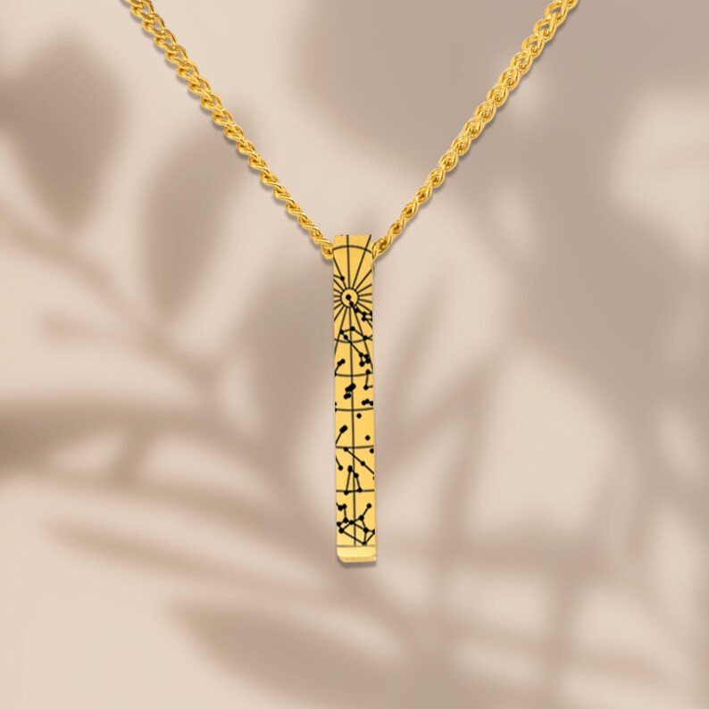 A gold necklace with a pendant featuring a geometric design.