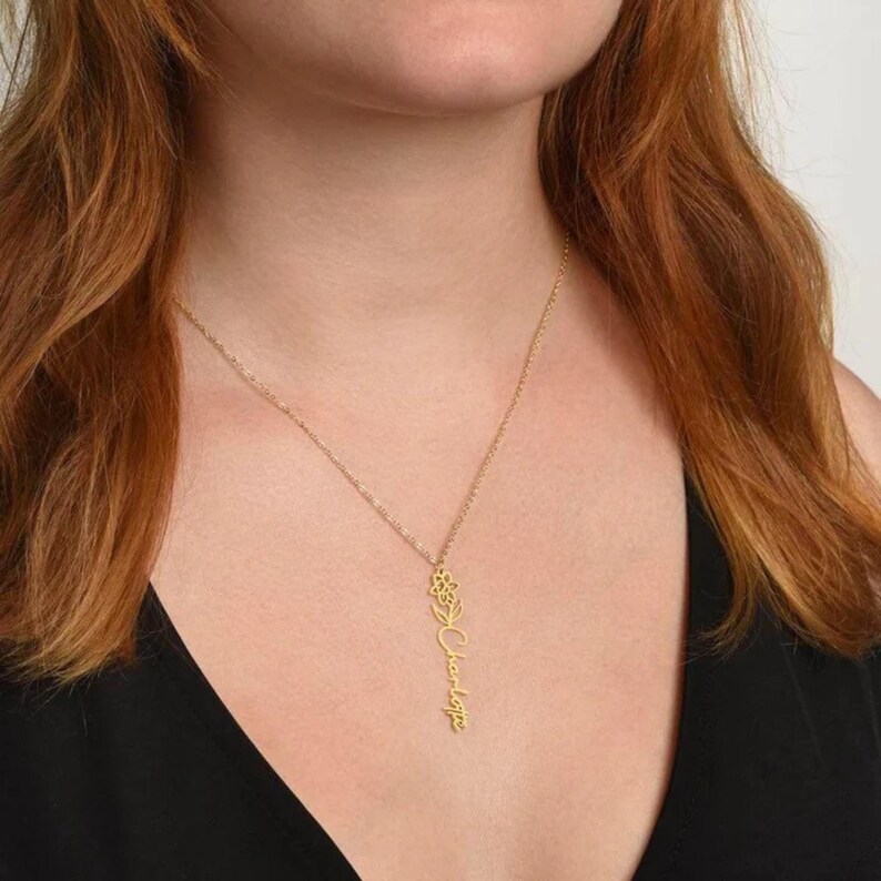 a woman with red hair wearing a black top and a gold necklace