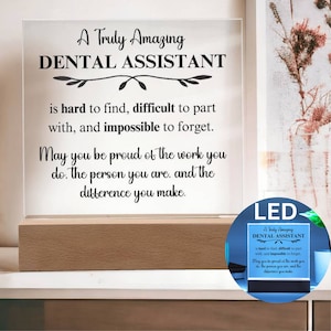 Op de afbeelding: Een witte acrylplaat met een zwarte inscriptie die luidt: "A Truly Amazing Dental Assistant is hard to find, difficult to part with, and impossible to forget. May you be proud of the work you do. The person you are. and the difference you make." De plaat wordt verlicht met LED-verlichting en staat op een houten voet.