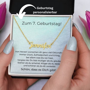 Puede incluir: Un collar de oro con una placa de nombre personalizada que dice "Jennifer". El collar está en una caja blanca con un fondo rosa y azul. La caja tiene un mensaje que dice "Zum 7. Geburtstag!" que se traduce como "¡Feliz cumpleaños número 7!" en español. La caja también tiene el texto "Geburtstag personalisierbar" que se traduce como "Cumpleaños personalizable" en español.