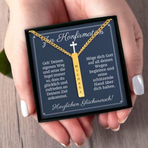 a person's hands holding a necklace with a personalized message on it. The message is in German and appears to be a confirmation or greeting for Michael.