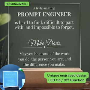 Op de afbeelding: Een gepersonaliseerde LED-lamp met een houten voet. Het heldere acryl paneel is gegraveerd met de tekst "PROMPT ENGINEER" en een persoonlijke boodschap. De lamp heeft een aan/uit-functie en een uniek gegraveerd ontwerp.