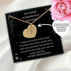 May include: A gold heart necklace with a star-filled design inside the heart. The necklace is in a black box with a message that reads "An unsere wundervolle Tochter" and "Vergiss nie: Du bist wunderschön, mit jedem deiner Fehler. Du bist stark, auch wenn du denkst, dass dir alles zu viel wird. Du bist mutig, auch wenn dir mal der Mut fehlt. Du bist einzigartig!"  The box also includes the text "Wir gravieren individuell den Sternenhimmel für Sie. Personalisierter Sternenhimmel; Datum & Ort."