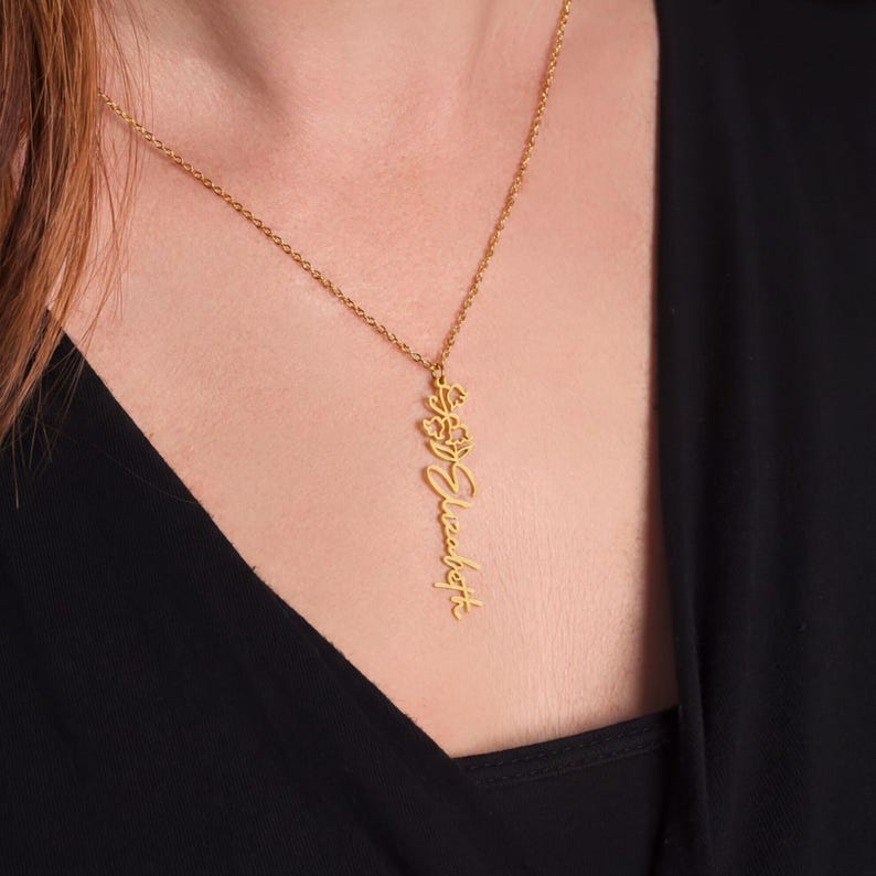 A gold necklace with a pendant featuring cursive text.