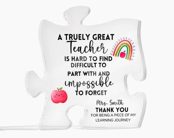 May include: A clear acrylic puzzle piece with a teacher appreciation message. The message reads "A truly great teacher is hard to find, difficult to part with and impossible to forget." The puzzle piece also features a rainbow and apple graphic. The text "Mrs. Smith Thank You for being a piece of my learning journey" is also included.
