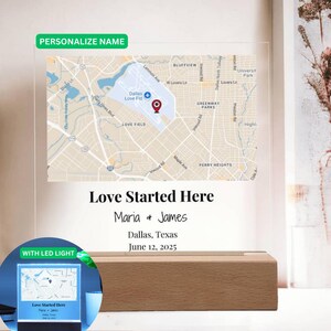 Puede incluir: Una pieza de arte de mapa personalizada con un mapa de Dallas, Texas, y el texto "Love Started Here" con nombres y una fecha. El mapa se muestra en un panel acrílico transparente, montado sobre una base de madera.