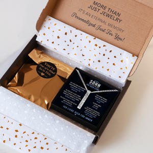 a gift box with a necklace and a card inside. The box is open, revealing the contents inside.