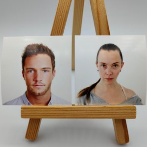 Op de afbeelding: Twee pasfoto's van mensen, een man en een vrouw, getoond op een houten ezel.