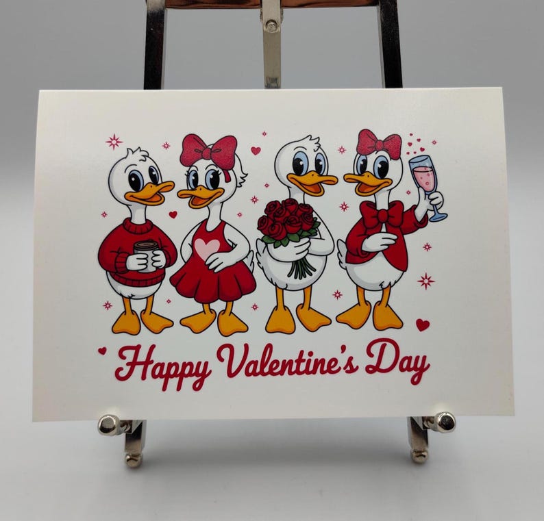 May include: A Valentine's Day card featuring four cartoon ducks. The ducks are dressed in red and white outfits, holding a coffee cup, flowers, and a glass of wine. The words "Happy Valentine's Day" are written in red script.