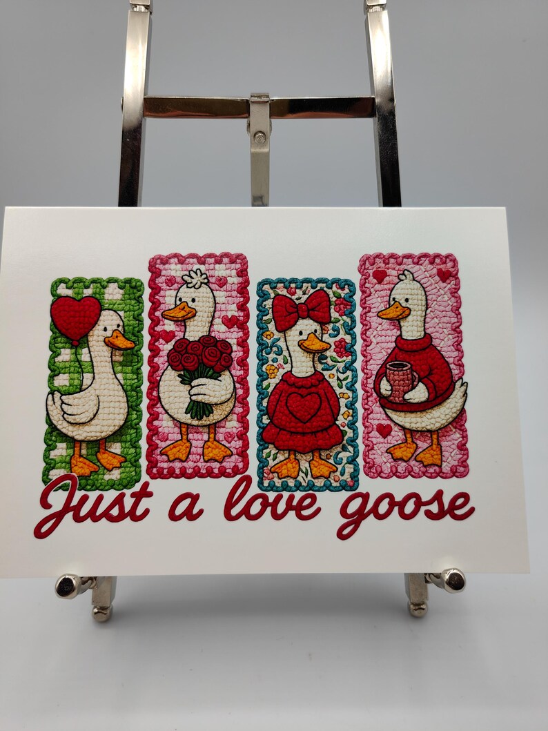 May include: A white card featuring four embroidered goose illustrations, each within a decorative frame. The geese hold a heart balloon, flowers, a bow, and a mug. The text "Just a love goose" is written in red script.