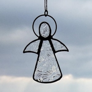 May include: A white stained glass angel ornament with a black outline. The angel has a halo and wings. The ornament is hanging from a string.