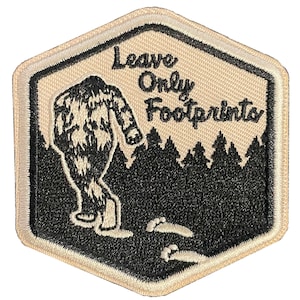 May include: A beige, hexagonal patch with a black border. The patch features a Bigfoot silhouette walking away from a forest scene. The text "Leave Only Footprints" is above the forest.