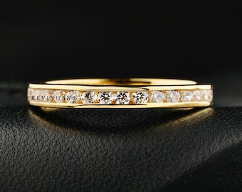 May include: A gold band ring with a row of small, clear diamonds set in a channel setting.