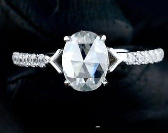 May include: A silver ring with a large oval-shaped diamond and a band of smaller diamonds.